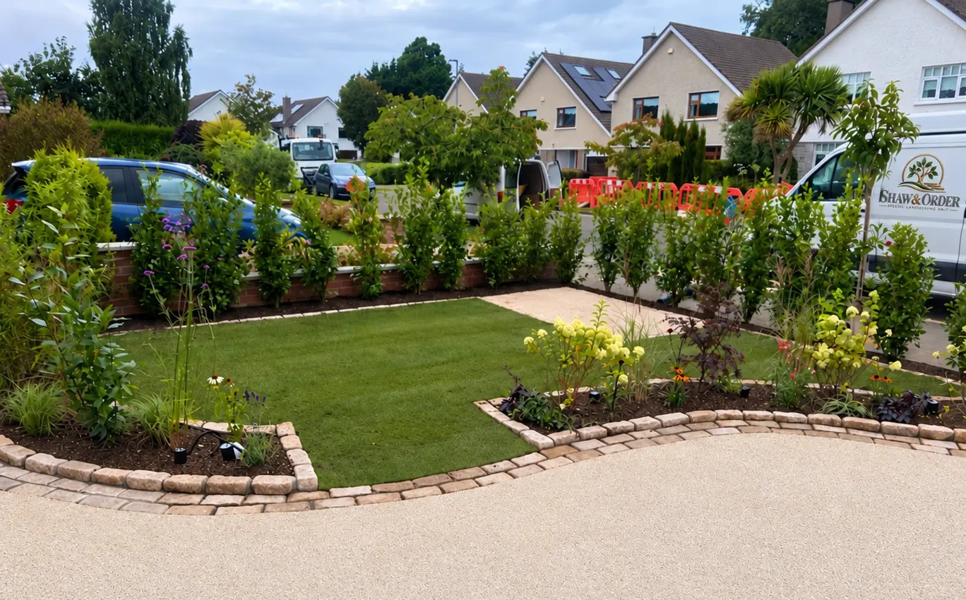 Newly landscaped front garden with a fresh lawn, planting beds and a clean new driveway